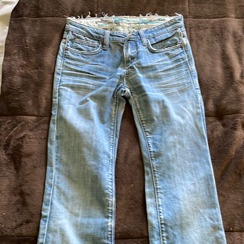 Vigoss women’s jeans. Embroidered design on pockets. Light blue worn in denim.